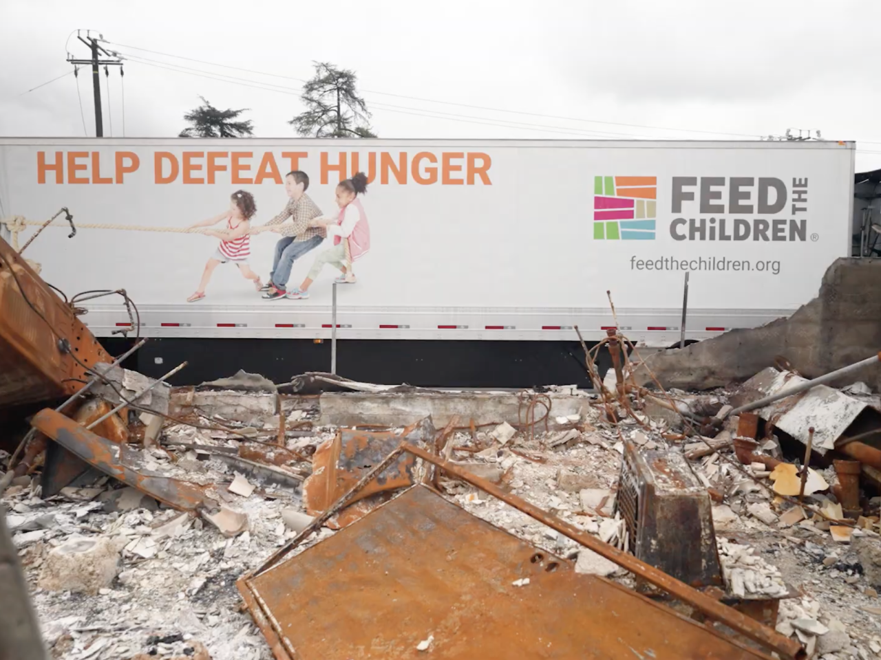 Feed the Children truck behind burnt structure