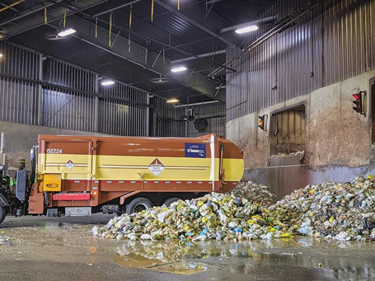 Garbage truck in a bay next to piles of garbage