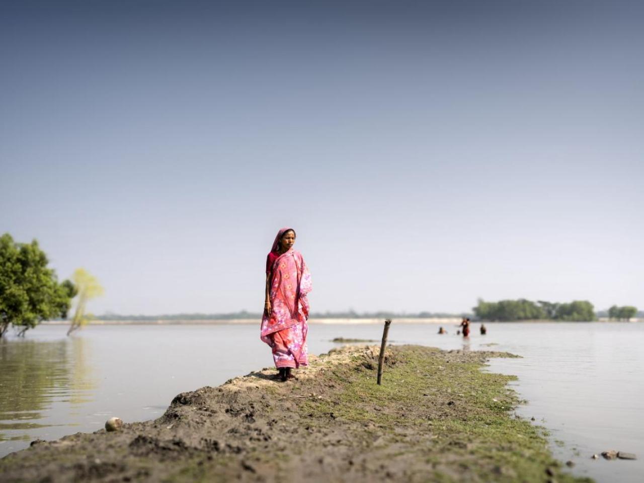 A woman walks along a flooded field. 