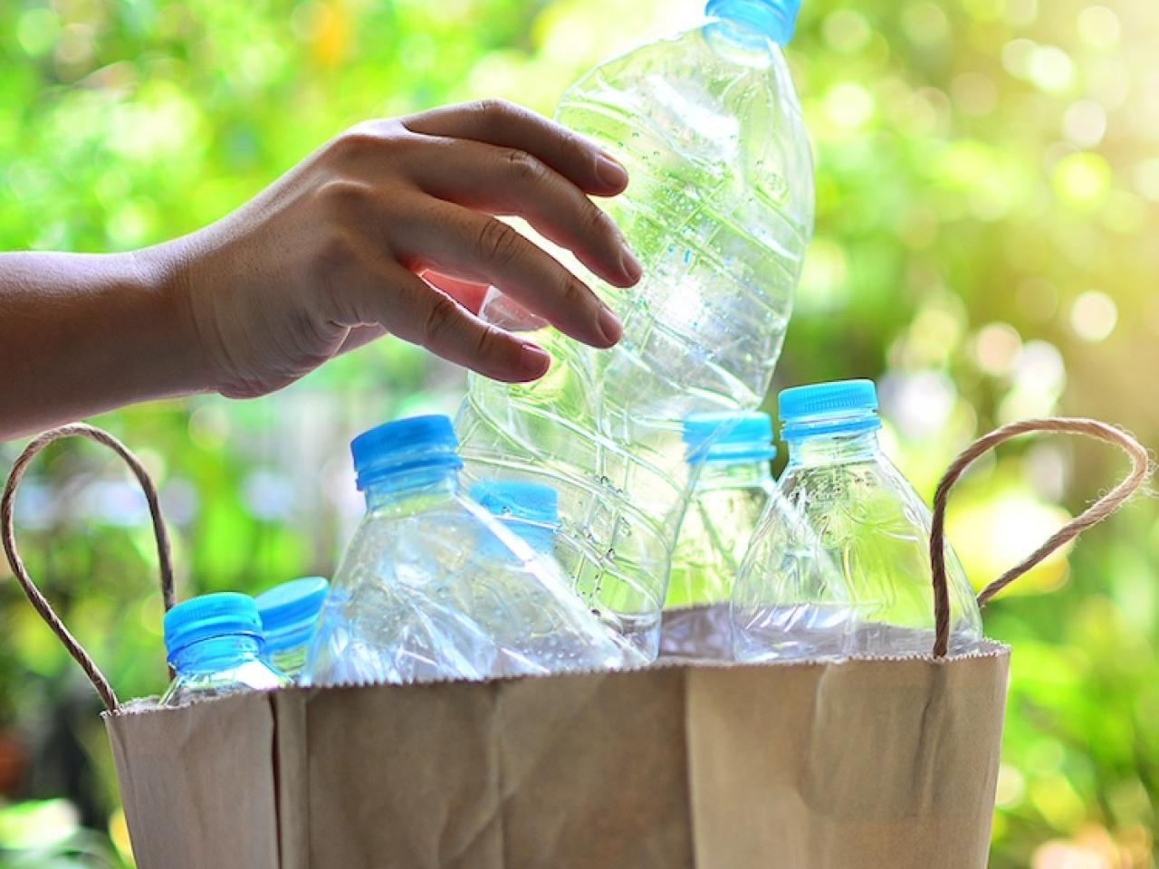 Empty plastic bottles being put into a recycling bag.