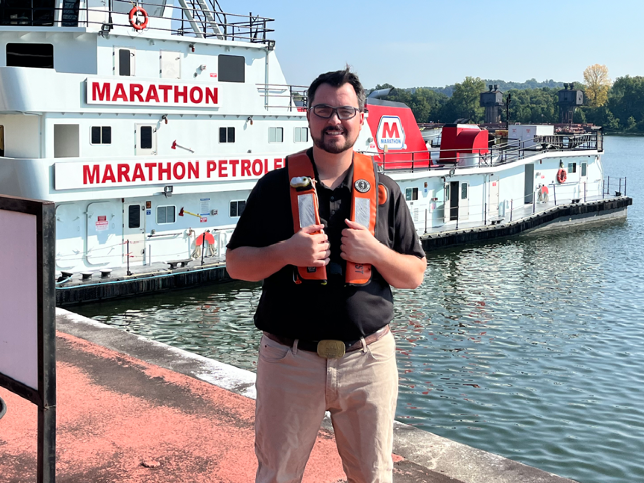 Wesley Rhoden wearing a life vest standing on a pier, a Marathon boat behind them.