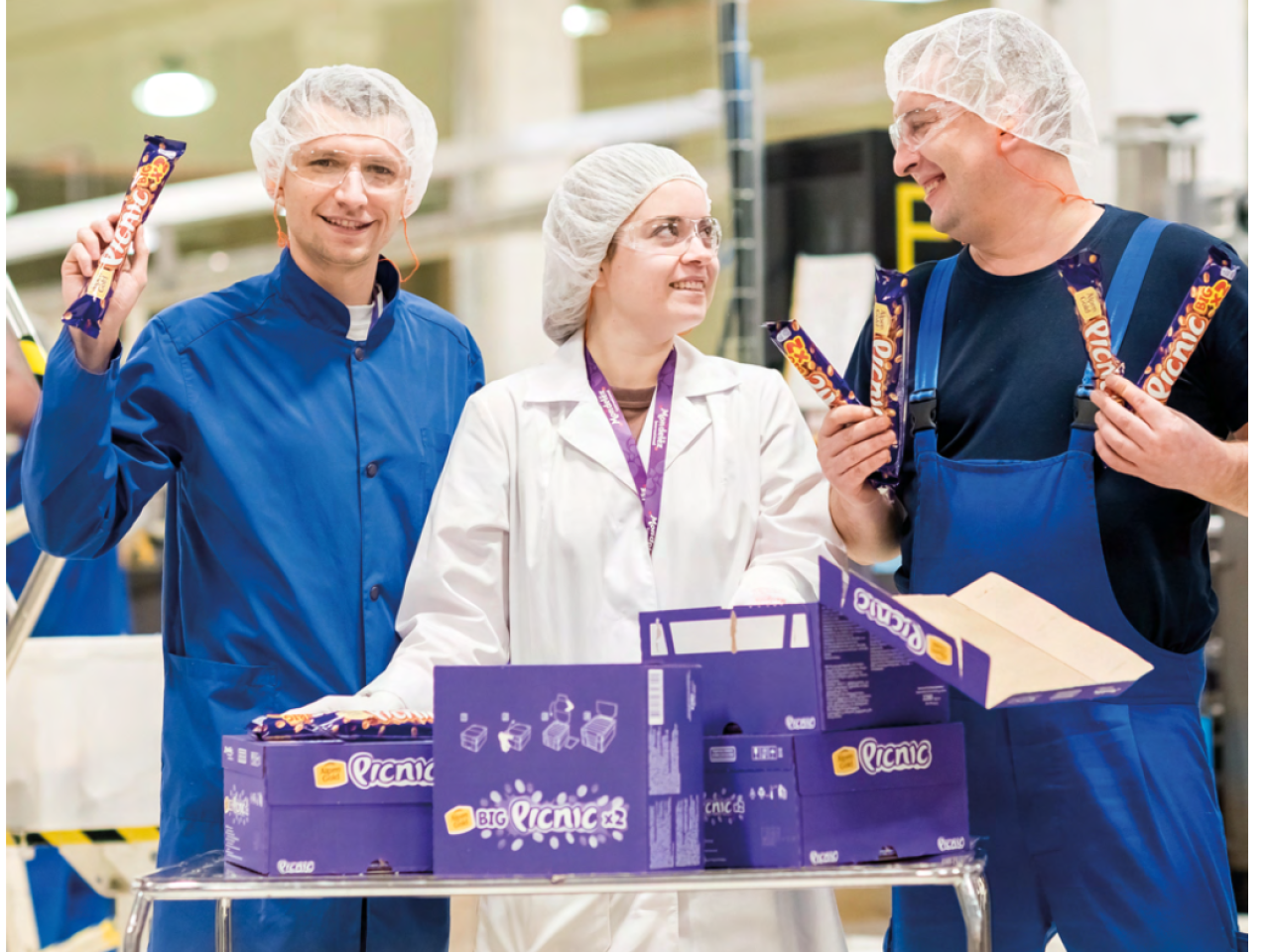 Three workers in their uniforms holding Mondelēz products