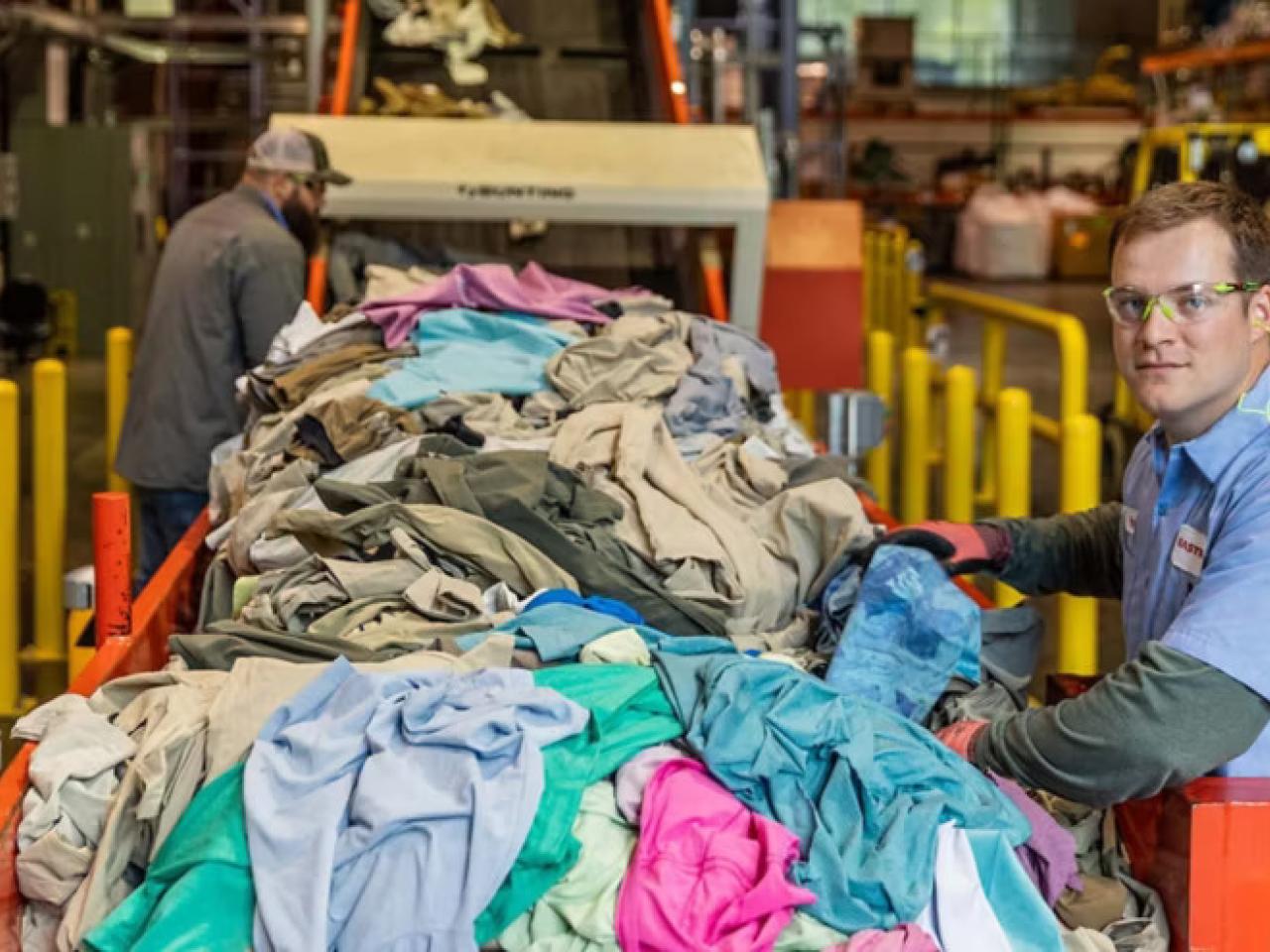 A person next to a line of waste textiles.
