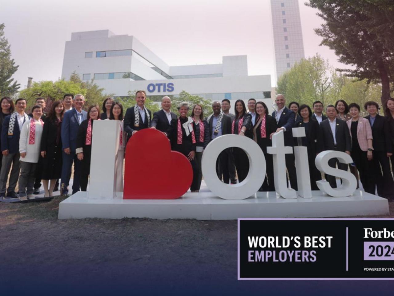 A large group posed outtside, behind a "I 'heart' Otis" sign. Forbes 2024 World's Best Employers logo in the corner.