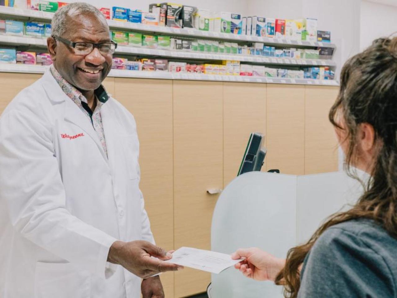 Calvin Bryant, pharmacist, handing something to a customer.