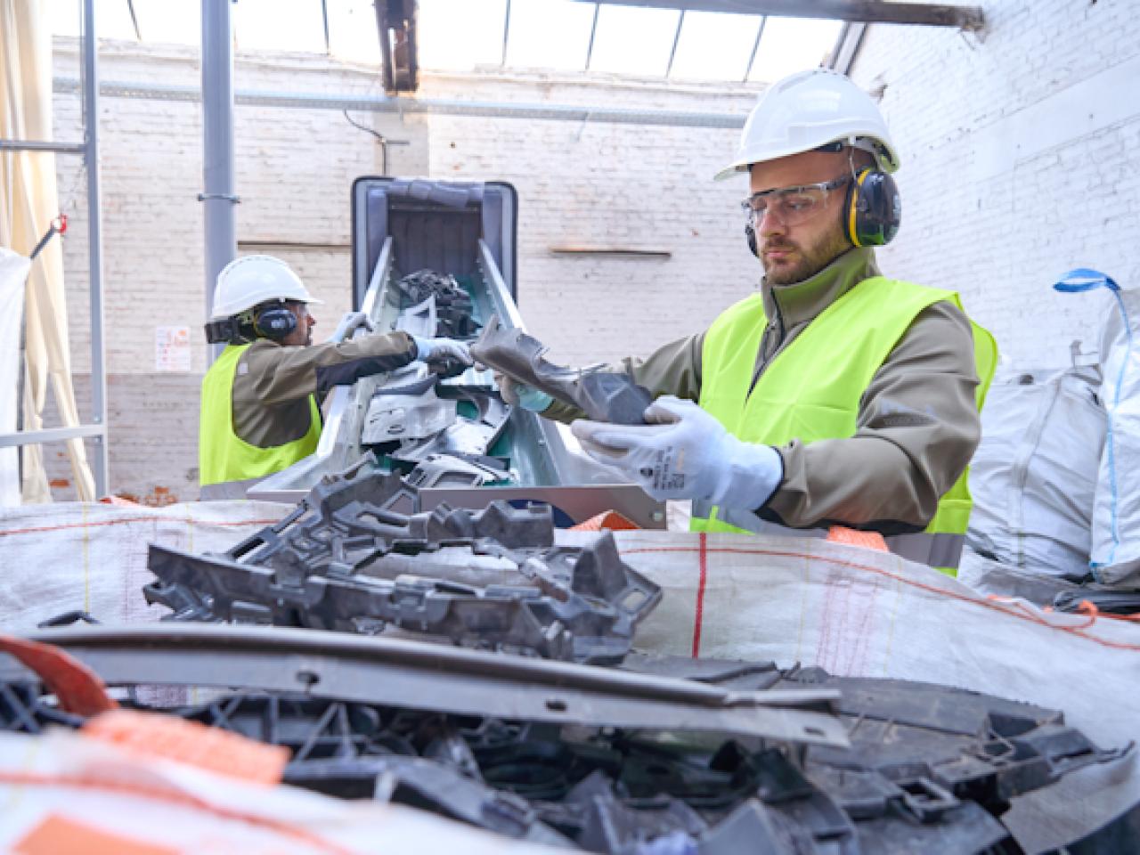 Workers sorting plastics on a conveyor belt.