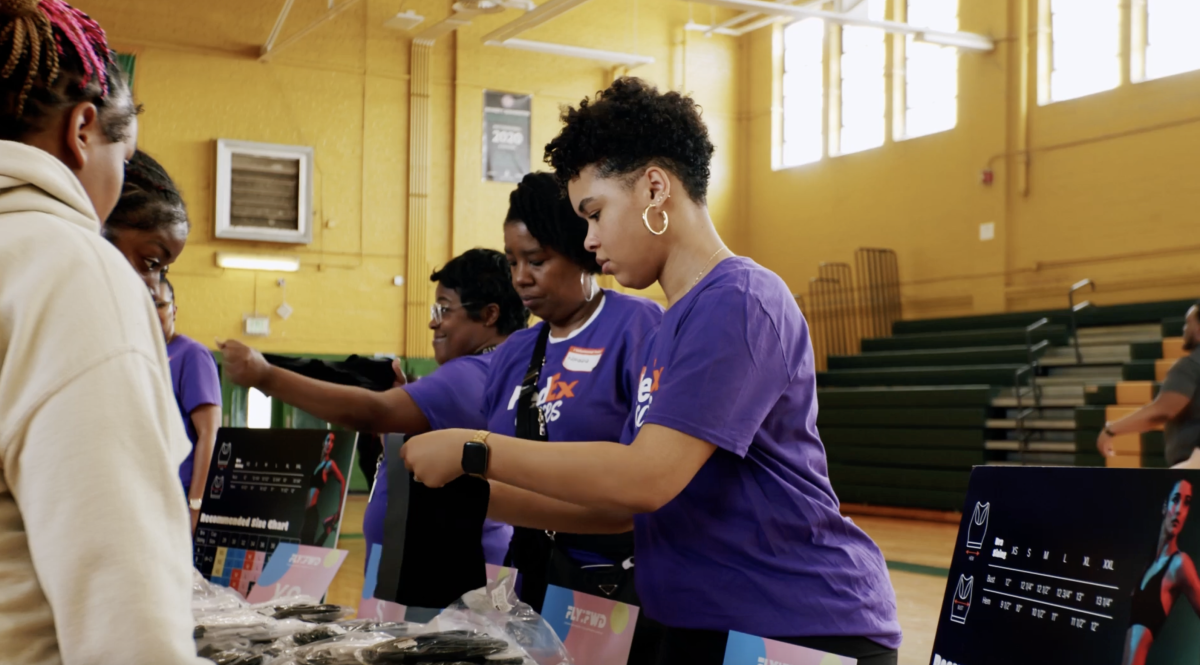 Girls wearing FedEx shirts at a table inside a gym