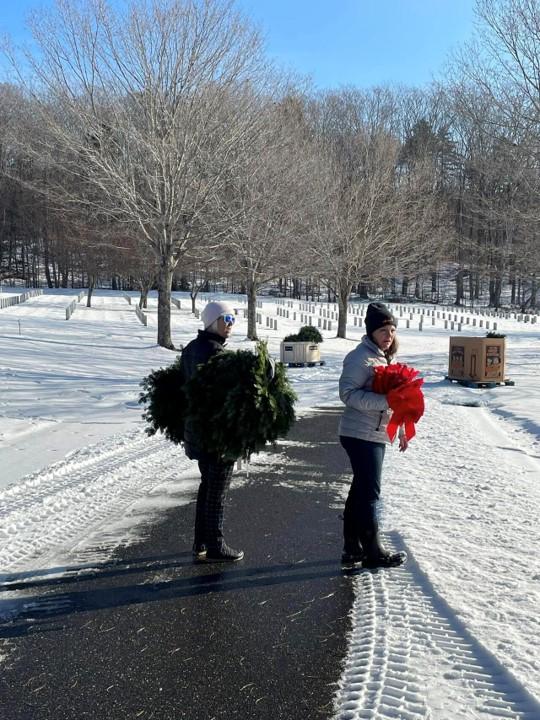 Two people holding wreaths and ribbons 