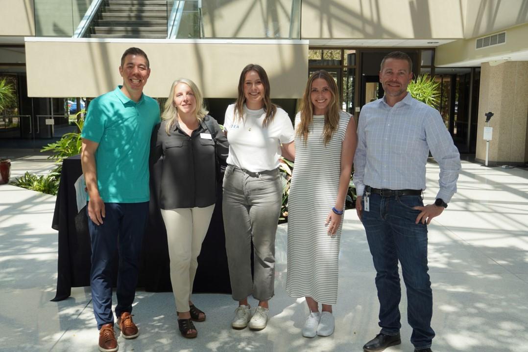 Five people posing for picture in office