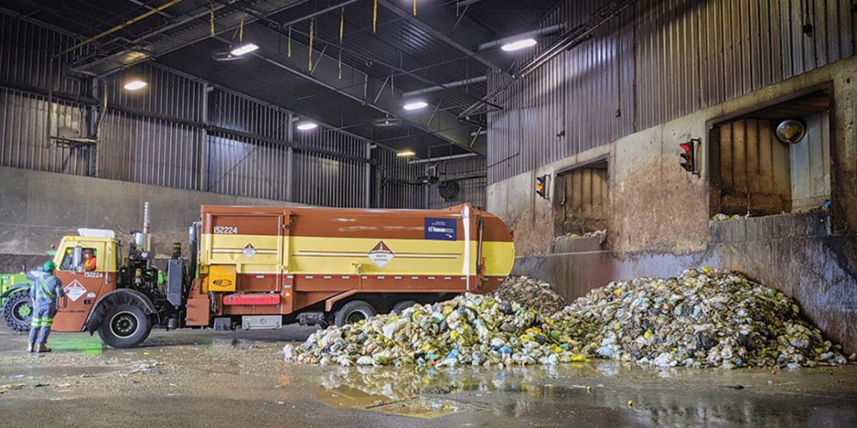 Garbage truck in a bay next to piles of garbage