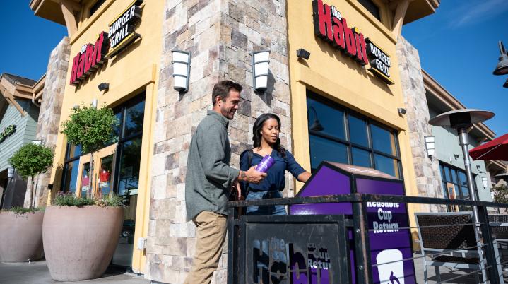 Two people returning cups outside of a restaurant