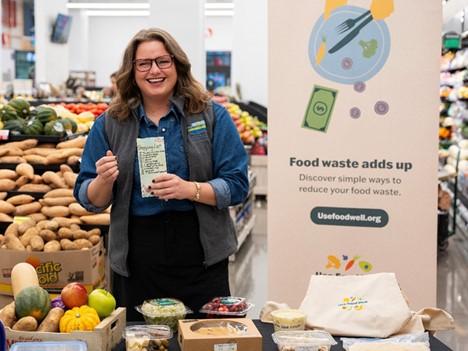 Person at grocery store with stand about food waste prevention