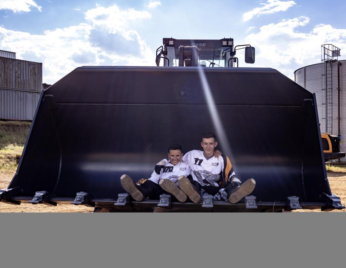 Two young people sat on a piece of agricultural equipment 