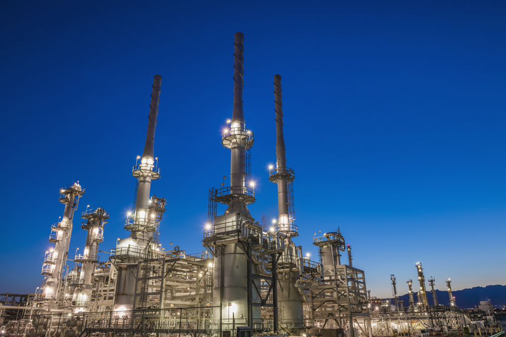 oil refinery illuminated by floodlights at dawn
