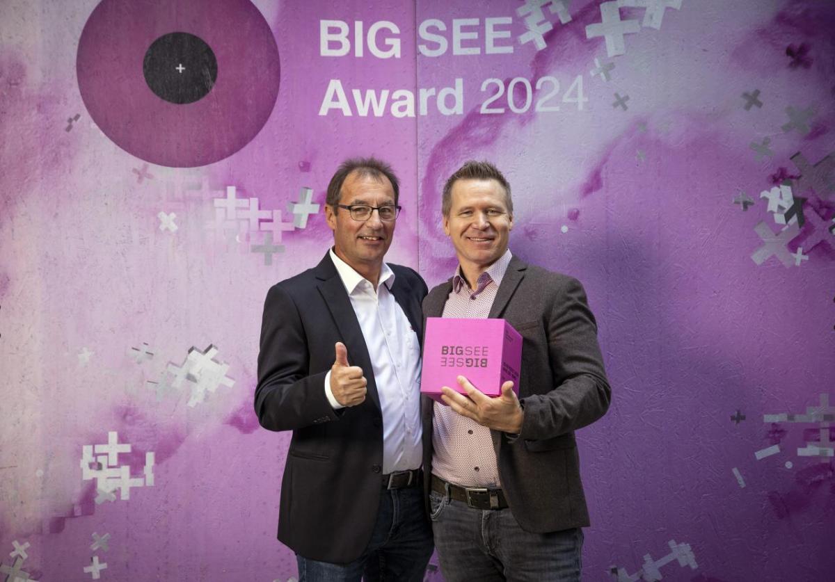 Two people stood together holding an award 