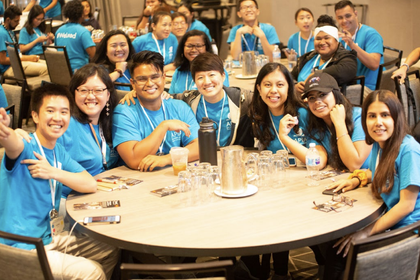 Students wearing blue t-shirts sat at round tables 