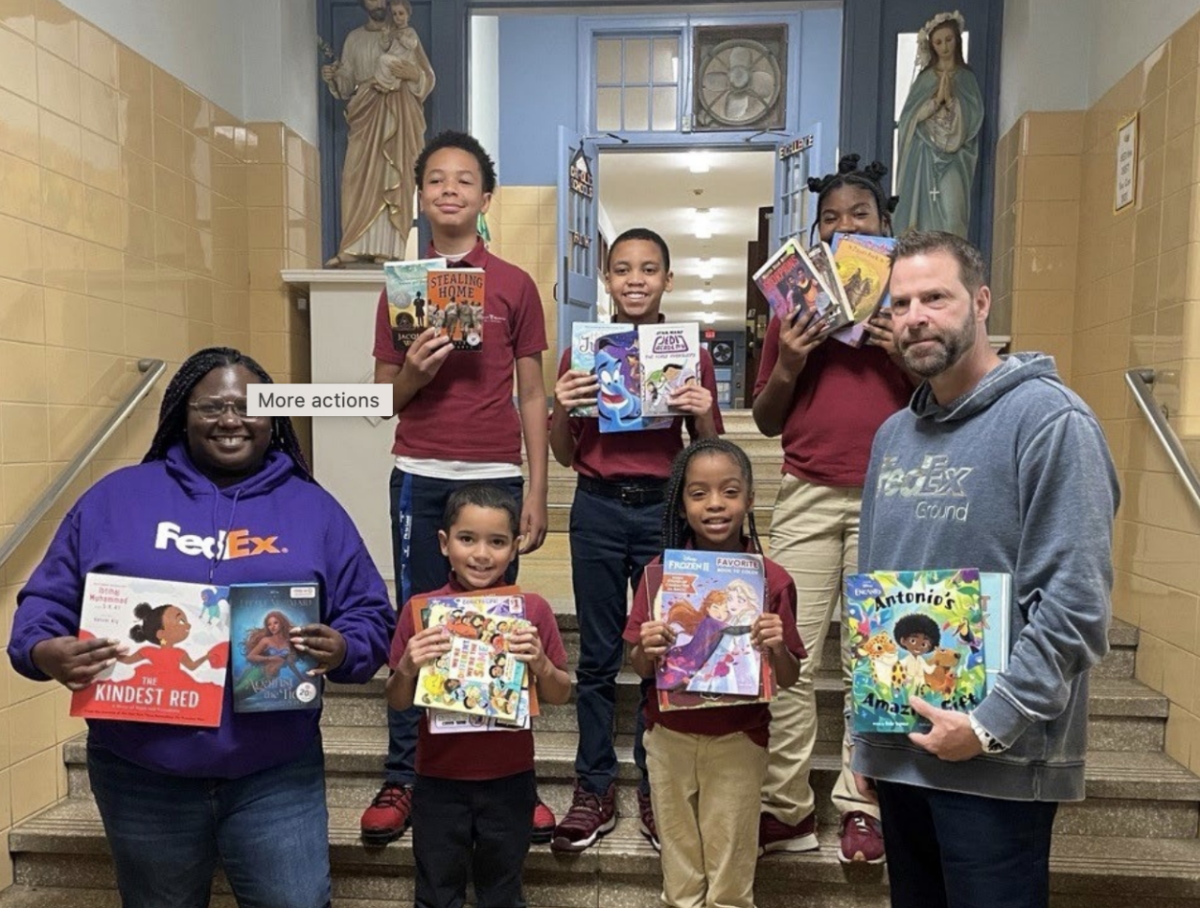 Two adults and five children stood on steps holding multiple books 