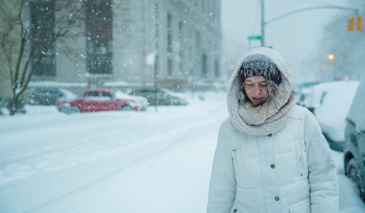 Woman shown in an extreme snow storm in a city.