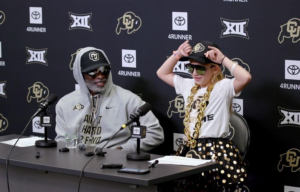 Coach Prime and Piper seated at a table.