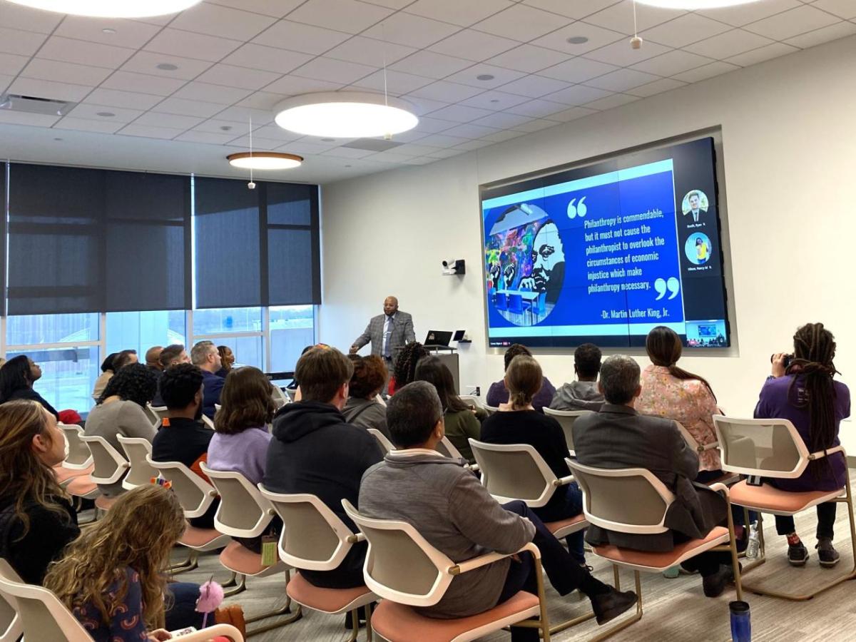 An audience of people sat on chairs facing a project board during an event