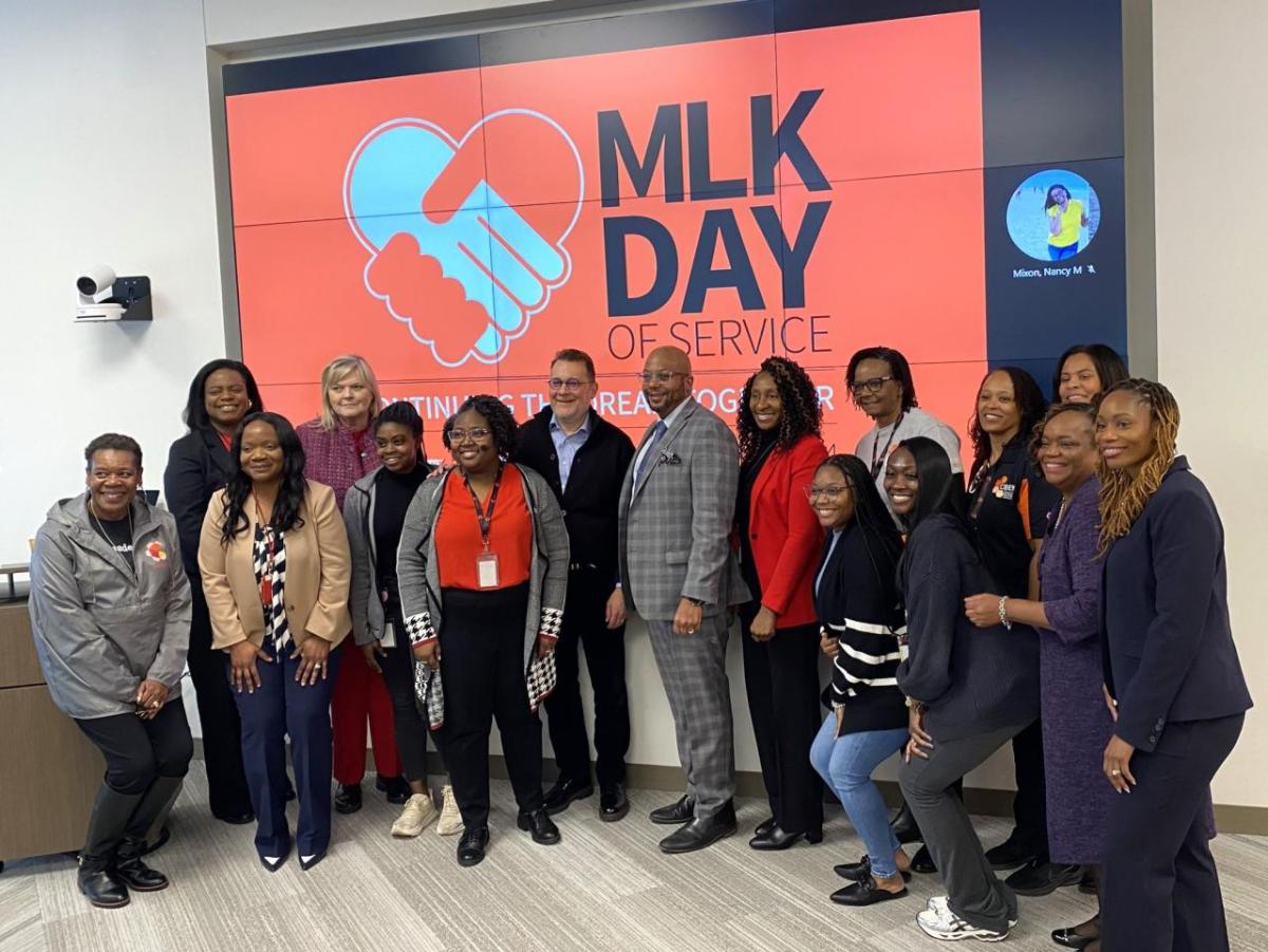 A group of people stood together in front of a projector board that reads "MLK DAY OF SERVICE"