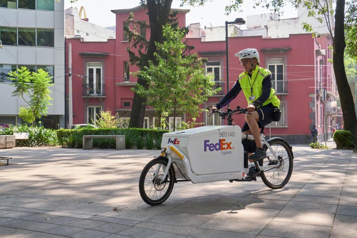 Person riding a FedEx bike outside with buildings and tree's behind them