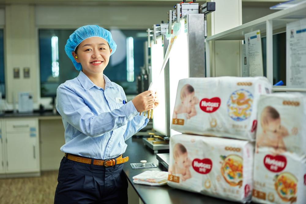 Kimberly-Clark employee standing next to Huggies diapers