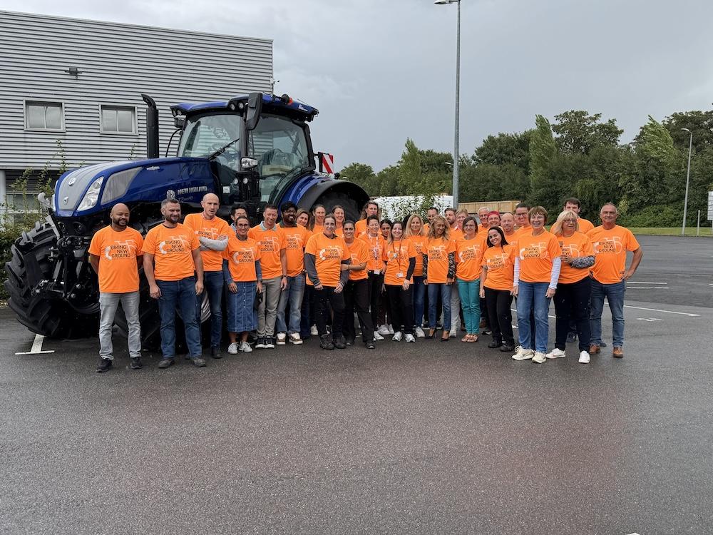 Group photo of participants in orange shirts in front of large tractor