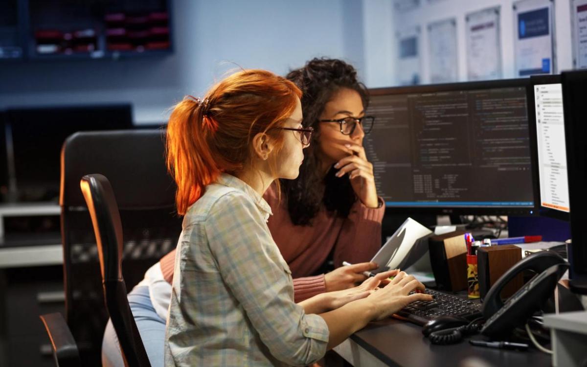 Two women staring at a computer screen.