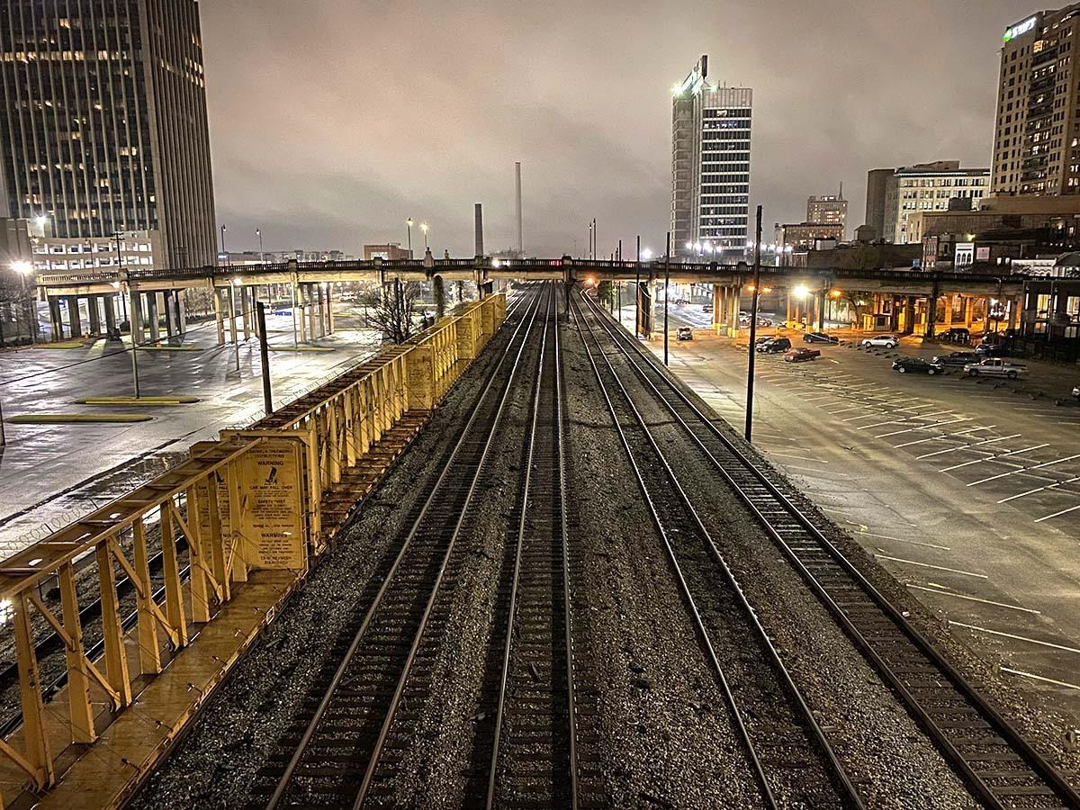 Dark and cloudy city landscape at night with railroad tracks in Indianapolis.