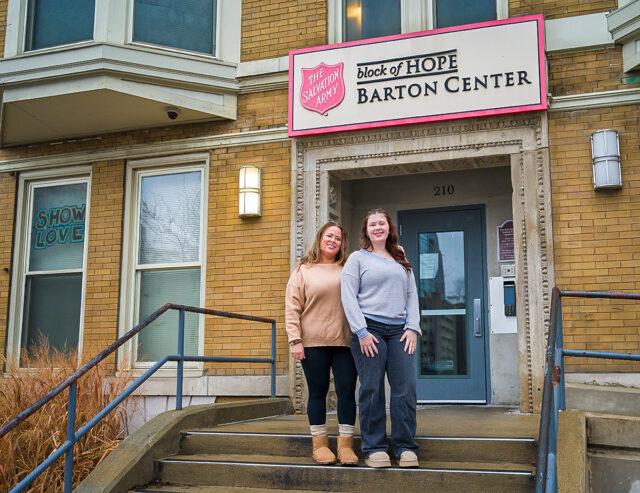 Picture of Amanda Henriott and Layknn Davidson standing next to eachother in front of The Salvation Army, block of Hope Barton Center entrace.