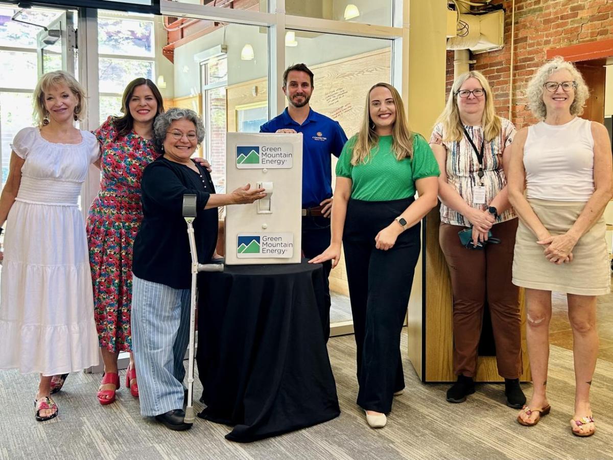 Members of Cancer Bridges, Connected Energy Solar, and Green Mountain Energy Sun Club "Flipping the Switch" with a life-size light switch.