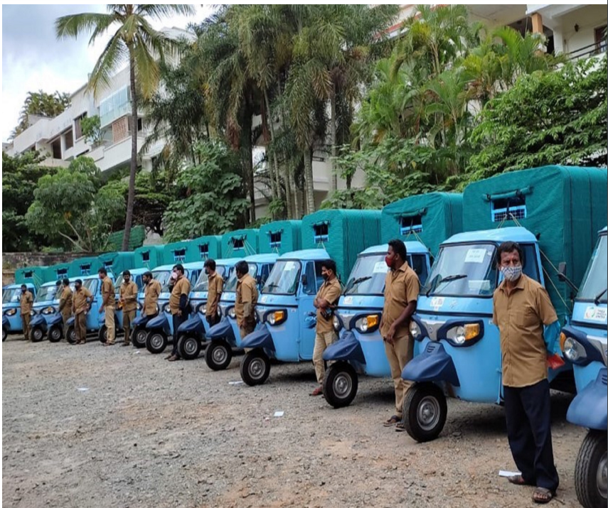 A row of identical small vehicles with drivers standing to the side.