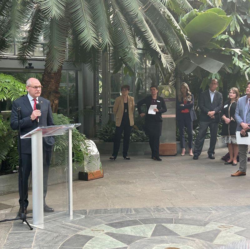 Jon Banner speaking at an outdoor podium.