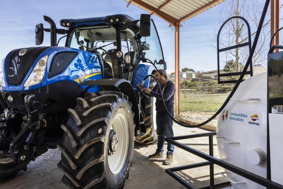 A person refueling a New Holland tractor