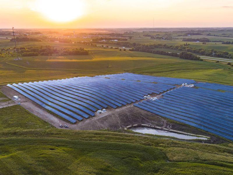 Solar panel array shown overhead with sun setting in the distance.