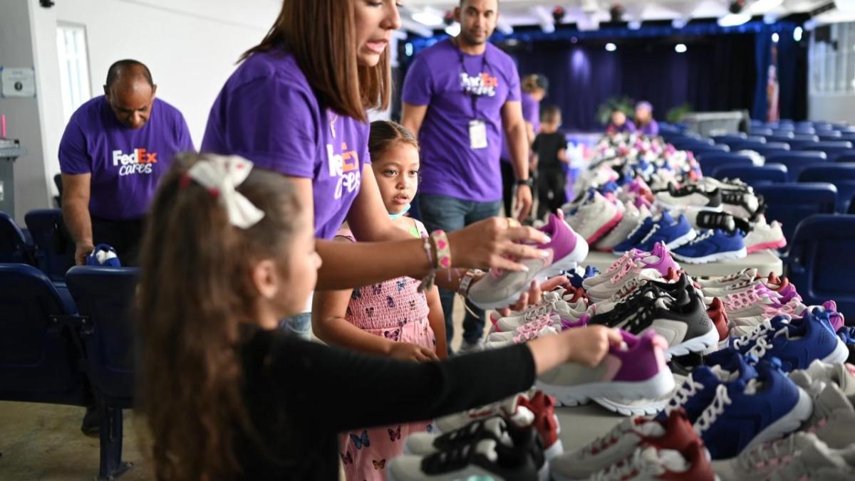 Children and volunteers in front of a table full of shoes