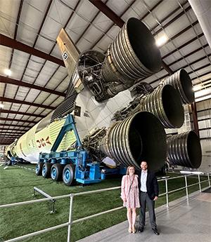 Adam Sanders and partner Kasey Wilson in front of the Saturn V rocket at NASA's Johnson Space Center.