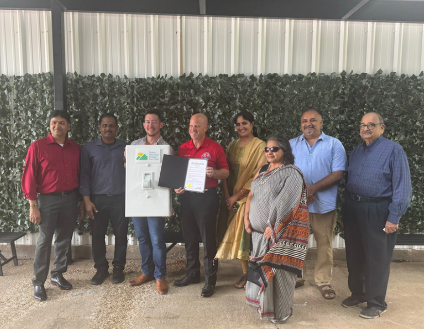 Group of diverse people standing and holding an oversized prop light switch and piece of paper