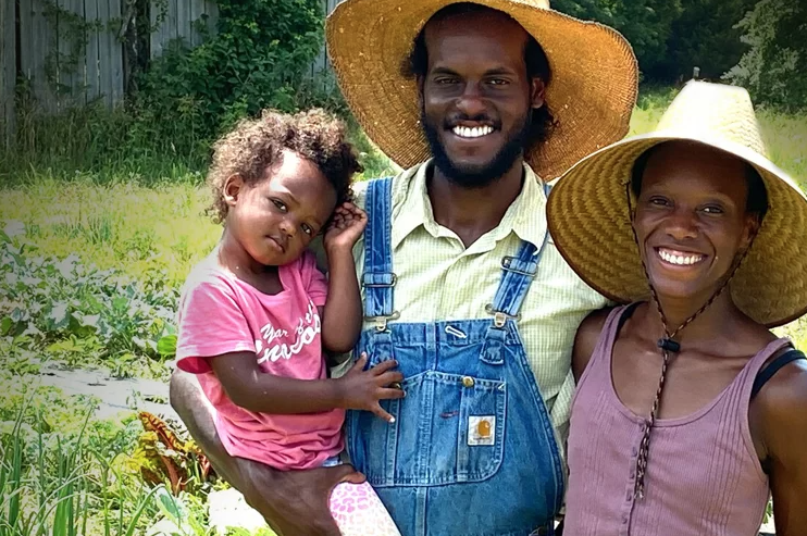 2 parents smile while holding their child