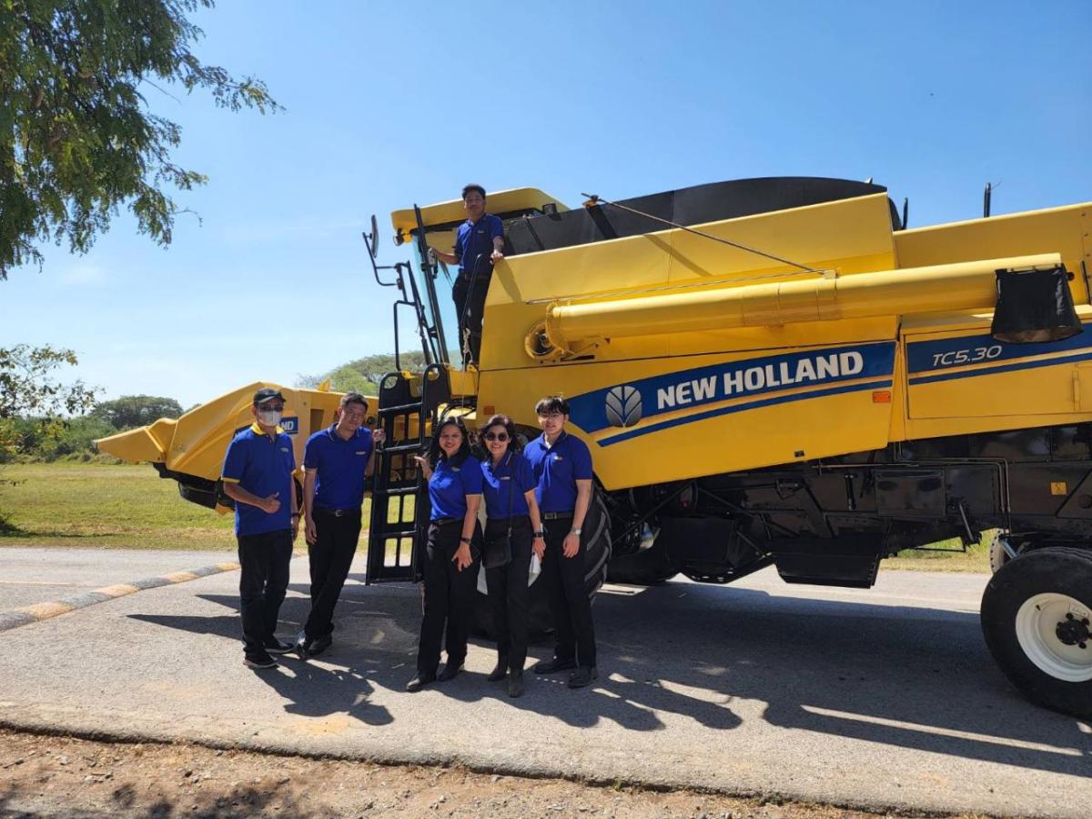 Five students standing in front of a New Holland Tractor