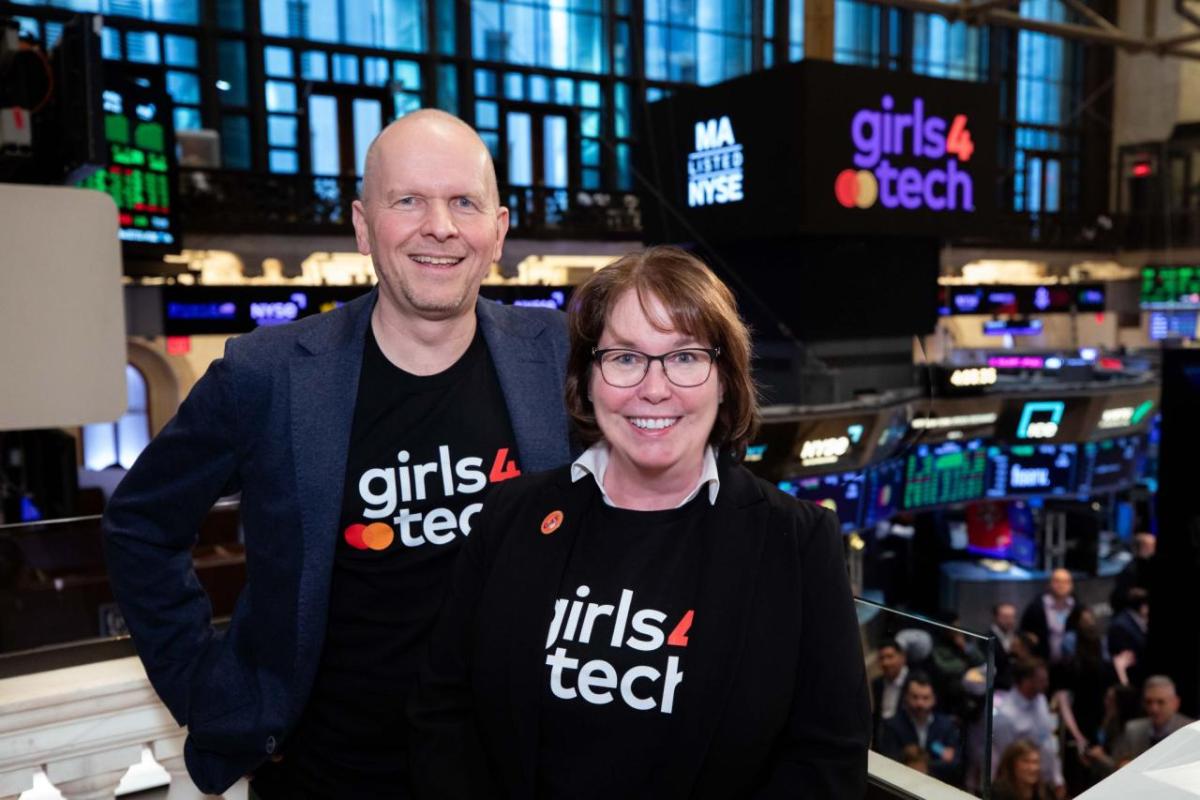 Two people posed looking above the floor of the new york stock exchange.