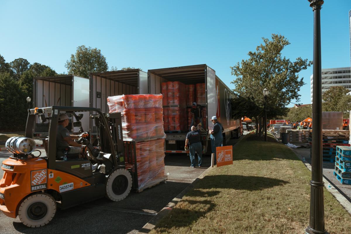 Forklifts loading pallets of supplies onto trucks.