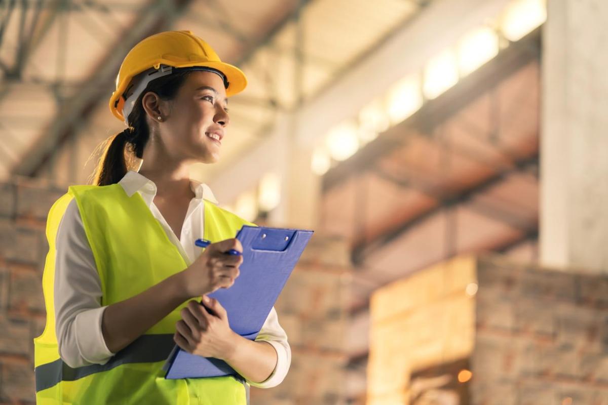 Woman wearing hard hat and holding clipboard