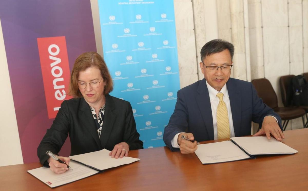 Two people seated at desk, signing letters