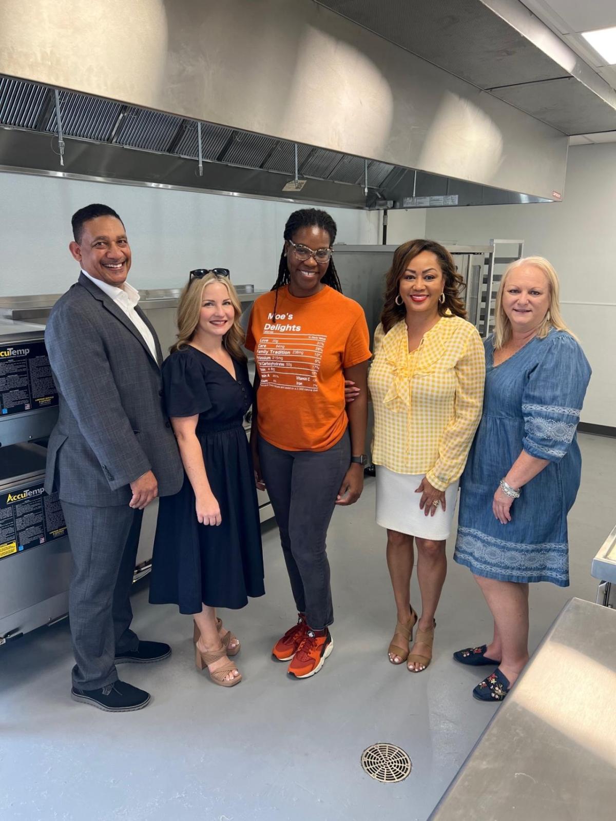 A group of five posed inside the kitchen of the facility.