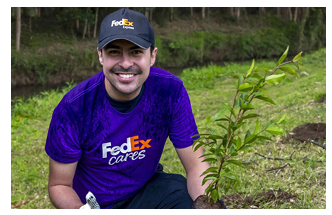 A volunteer next to a small tree in the ground.