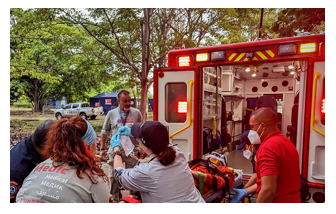 People helping lift a stretcher behind an ambulance.