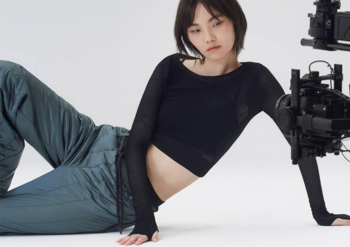 A model sitting on their side on the floor, a camera to the right