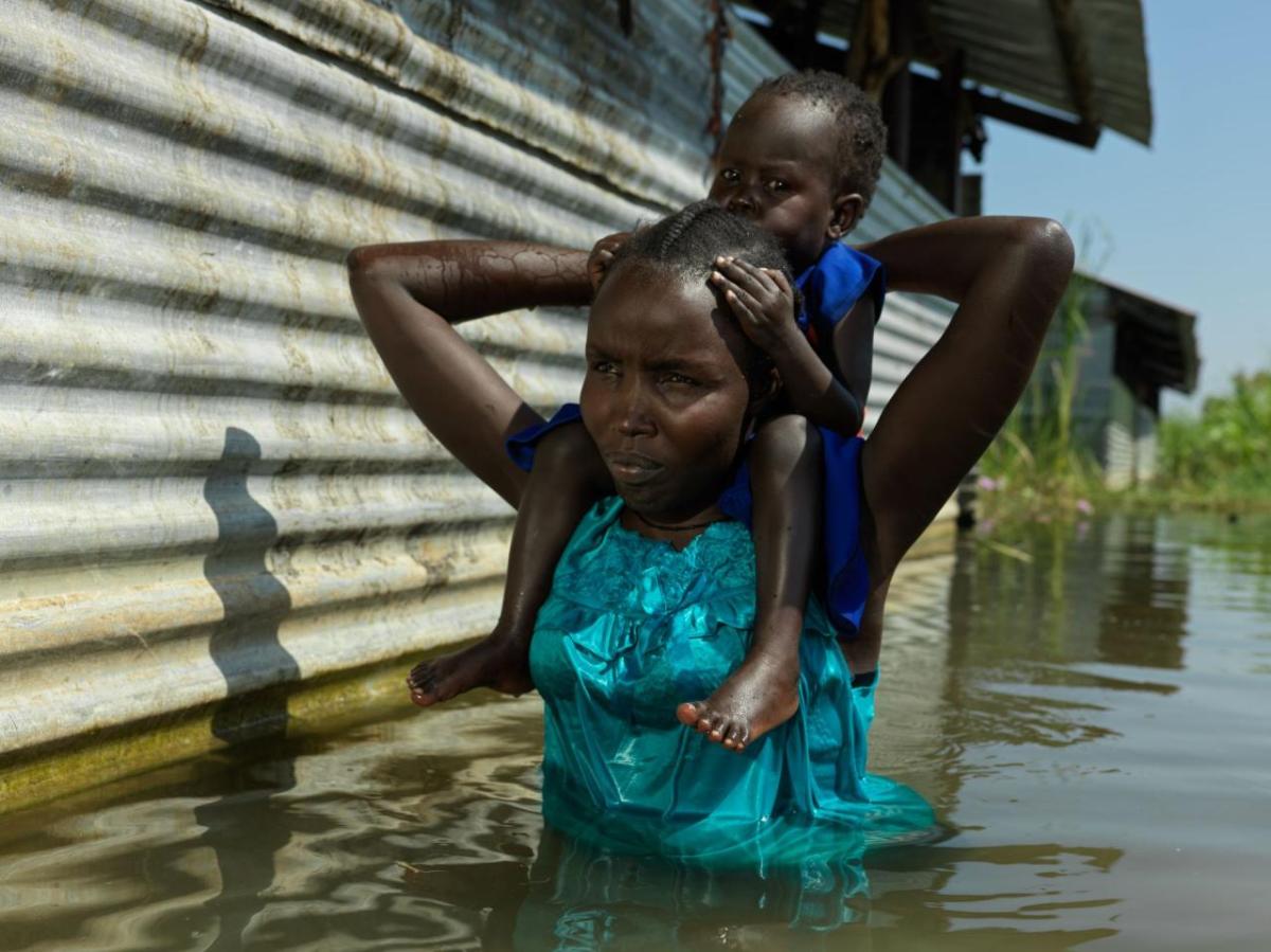 Aweng Thang wades through water with her daughter in Old Fangak.